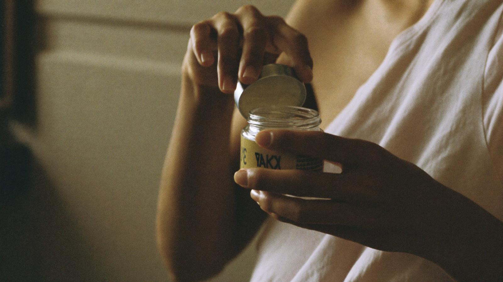 Opening a small jar of nipple balm — postpartum body care
