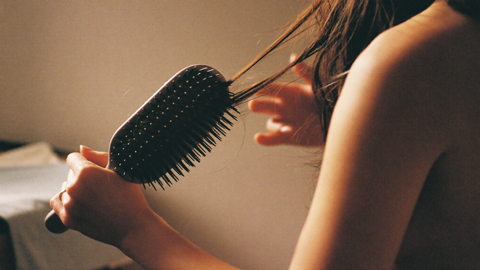 Postpartum hair loss — gently brushing hair, strands on the brush