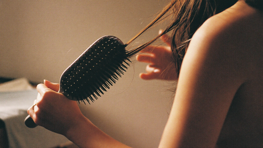 Postpartum hair loss — gently brushing hair, strands on the brush