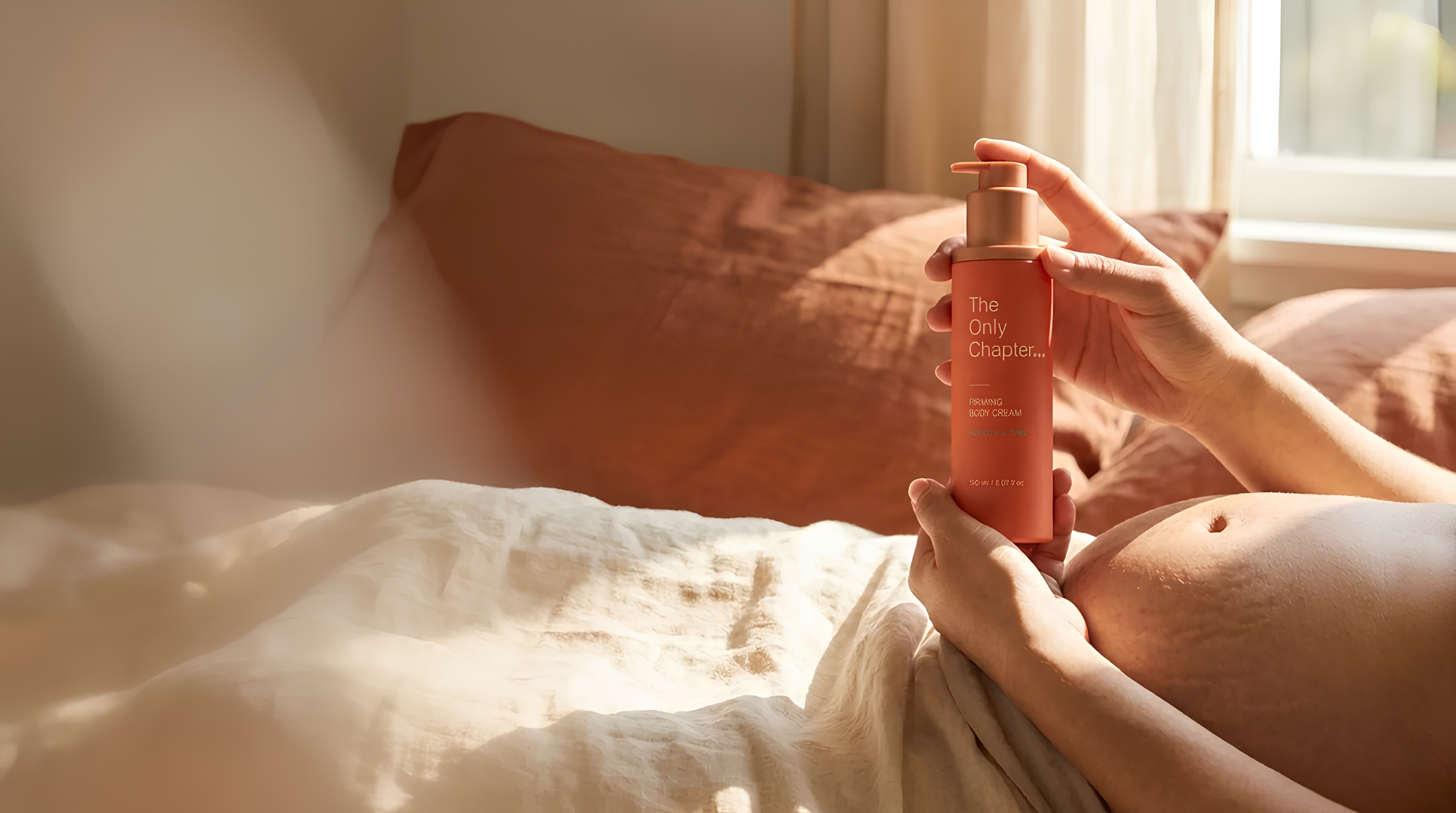 Hands cradling a postpartum belly with The Only Chapter Firming Body Cream